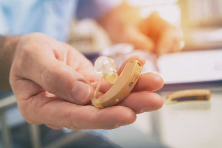 A hearing aid held in a person's hand